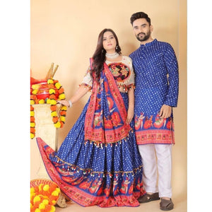 A couple modeling traditional Indian clothing, featuring a woman in a blue and red patterned lehenga choli with a matching dupatta, and a man in a matching blue kurta and white trousers, posed against a beige background with decorative marigold garlands.