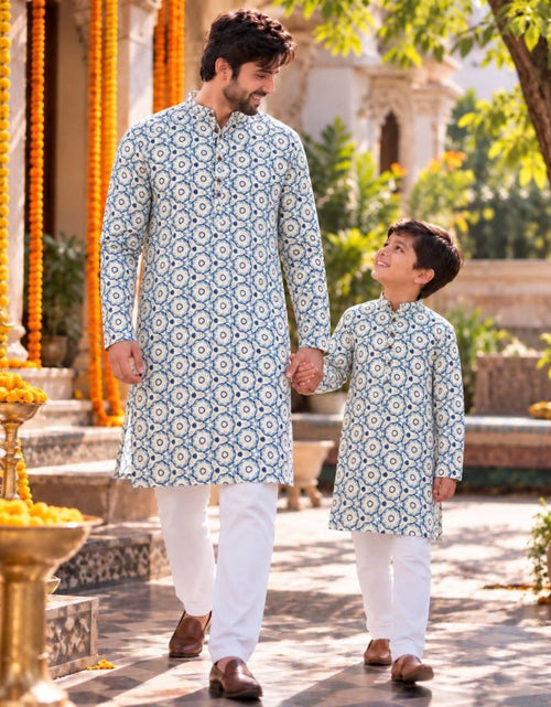Load image into Gallery viewer, A man and a boy walking hand-in-hand outdoors, wearing matching light blue and white patterned kurta sets with white trousers.
