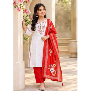 A woman models a traditional Indian salwar kameez suit set. The outfit consists of a white long kurta with red floral embroidery on the chest, paired with solid red pants and a matching red dupatta featuring a floral border and embroidered details.