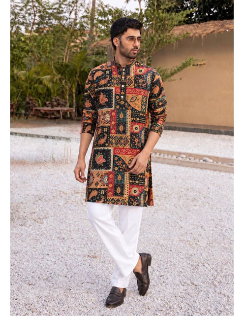 Load image into Gallery viewer, A man wearing a multicolor patchwork kurta with red, orange, and black patterns, paired with white trousers and dark brown loafers, walking outdoors on a gravel path.
