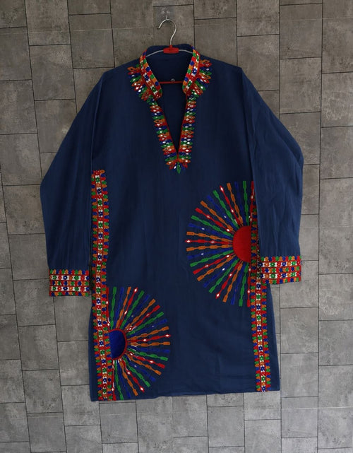 Load image into Gallery viewer, A navy blue long-sleeve tunic or kurta with colorful geometric embroidered patterns around the collar, cuffs, hem, and large sunburst motifs on the front, hanging against a gray tiled wall.
