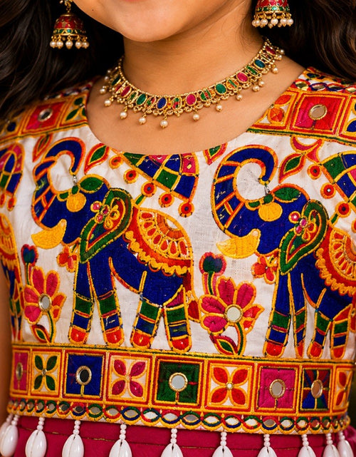 Load image into Gallery viewer, A close-up of a child wearing a sleeveless traditional outfit with colorful elephant and floral embroidery, along with matching earrings and a necklace.
