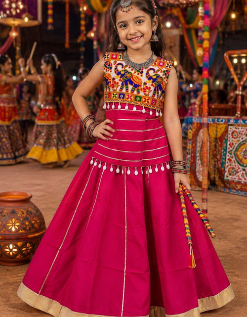 Load image into Gallery viewer, A young girl modeling a bright magenta pink traditional Indian lehenga choli dress with gold and multicolor embroidery, standing in a decorated festive indoor setting.

