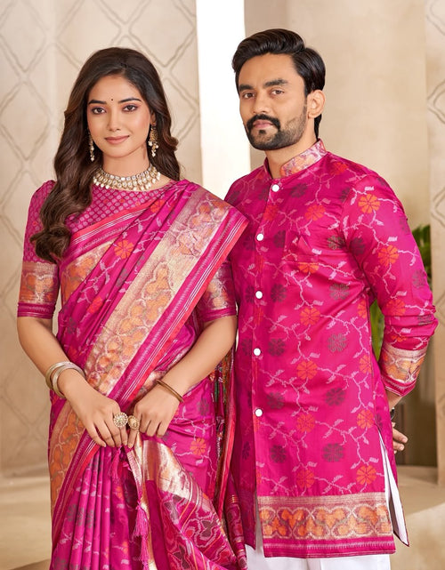 Load image into Gallery viewer, A man and a woman posing together in traditional Indian attire. The woman wears a vibrant pink and gold patterned saree, and the man wears a matching bright pink embroidered kurta over white trousers.
