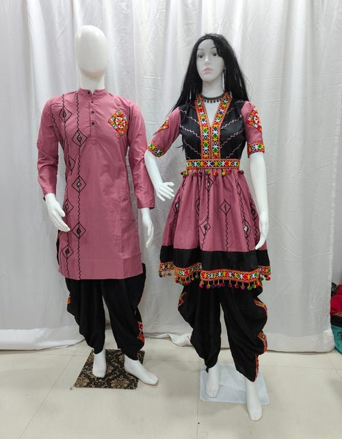 Load image into Gallery viewer, A traditional Indian Couple Wear outfit displayed on two mannequins against a white curtain backdrop. The set includes a men's pink kurta with black pants and a women's matching pink kurta with black pants, both featuring black harem-style pants and colorful embroidered details.
