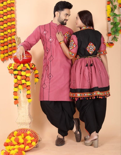 Load image into Gallery viewer, A man and a woman wearing matching traditional Indian ethnic wear, featuring pink and black kurta sets with colorful embroidery, posed in front of a decorated peach-colored backdrop with marigold garlands.

