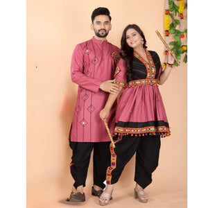 A man and a woman modeling traditional Indian ethnic Navratri couple matching wear. The man wears a dusty pink embroidered kurta with black pants, and the woman wears a matching dusty pink and black kurta with ornate gold and red embroidery, paired with black pants.