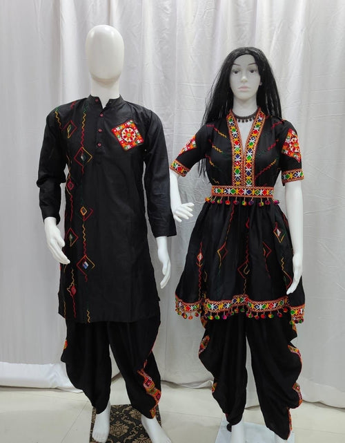 Load image into Gallery viewer, A traditional black embroidered couple wear Navratri kurta and pant set displayed on two mannequins against a white curtain backdrop. The Matching set features vibrant red, yellow, and green geometric embroidery on the chest, sleeves, and hem. 
