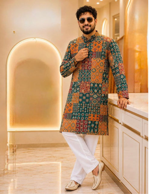 Load image into Gallery viewer, A man wearing a multicolor patchwork-patterned kurta with white trousers and beige shoes, posing in a modern, warmly lit interior setting.

