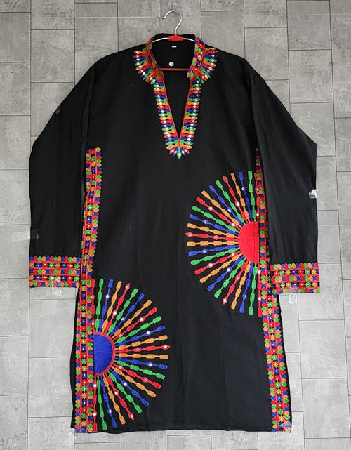 Load image into Gallery viewer, A black long-sleeve tunic or kaftan with vibrant multicolor embroidered geometric patterns, shown hanging against a gray tiled wall.
