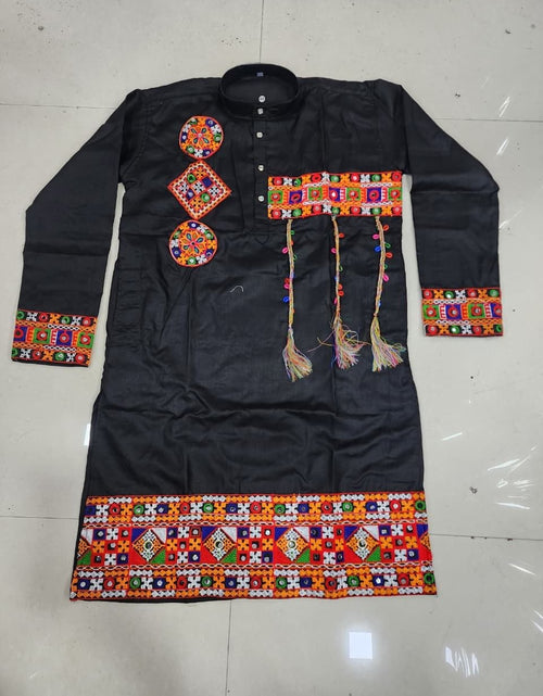Load image into Gallery viewer, A black long-sleeve traditional tunic or kurta laid flat on a light tiled floor, decorated with colorful geometric embroidered patterns on the chest, cuffs, hem, and hanging tassels.

