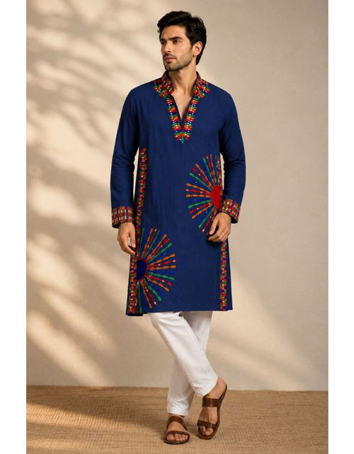 Load image into Gallery viewer, A man modeling a navy blue kurta with colorful embroidered patterns on the neckline, cuffs, and hem, paired with white trousers and brown sandals, set against a beige wall with soft shadow patterns.
