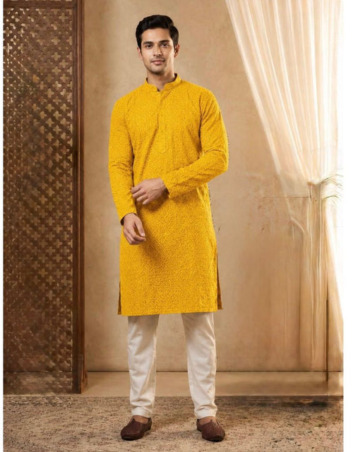 Load image into Gallery viewer, A man modeling a bright yellow long-sleeve kurta with white trousers and brown shoes, standing in a warm-toned indoor setting with patterned screens and draped curtains.
