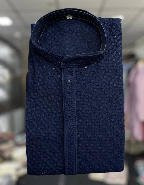 Load image into Gallery viewer, A folded navy blue textured kurta with a mandarin collar, displayed against a blurred indoor background.
