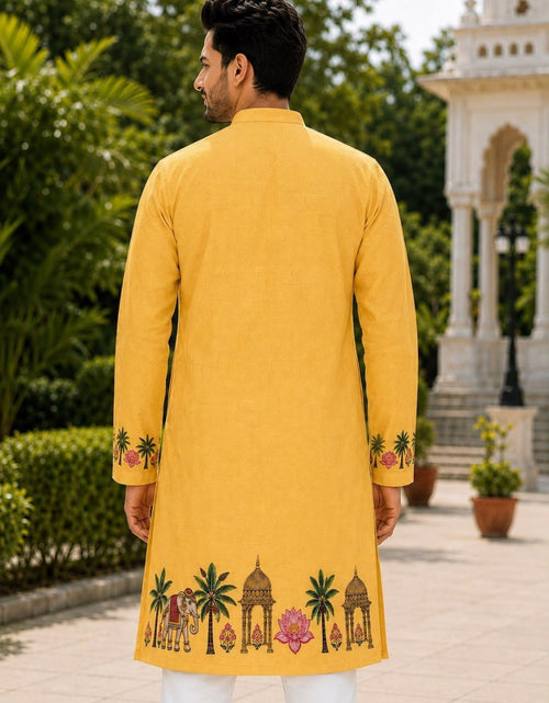 Load image into Gallery viewer, A man viewed from behind wearing a bright yellow kurta with colorful embroidered motifs of palm trees, domes, and lotus flowers near the hem and cuffs, set against a garden background with a white pavilion.
