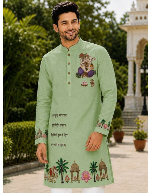 Load image into Gallery viewer, A man wearing a light green long-sleeve kurta with colorful traditional Indian illustrations and text on the chest and cuffs, standing outdoors in front of a garden and white architectural structure.
