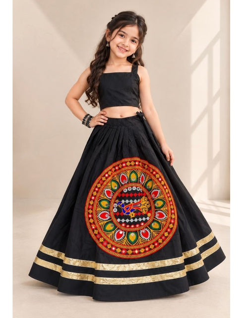 Load image into Gallery viewer, A young girl modeling a black traditional Indian ethnic wear set consisting of a sleeveless crop top and a flared skirt with a large colorful circular embroidered motif on the front and gold stripes near the hem.
