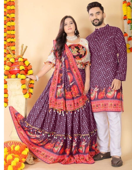 A couple modeling traditional Indian ethnic wear. The woman wears a deep purple embroidered lehenga choli with a red and orange border print, and a matching patterned dupatta.