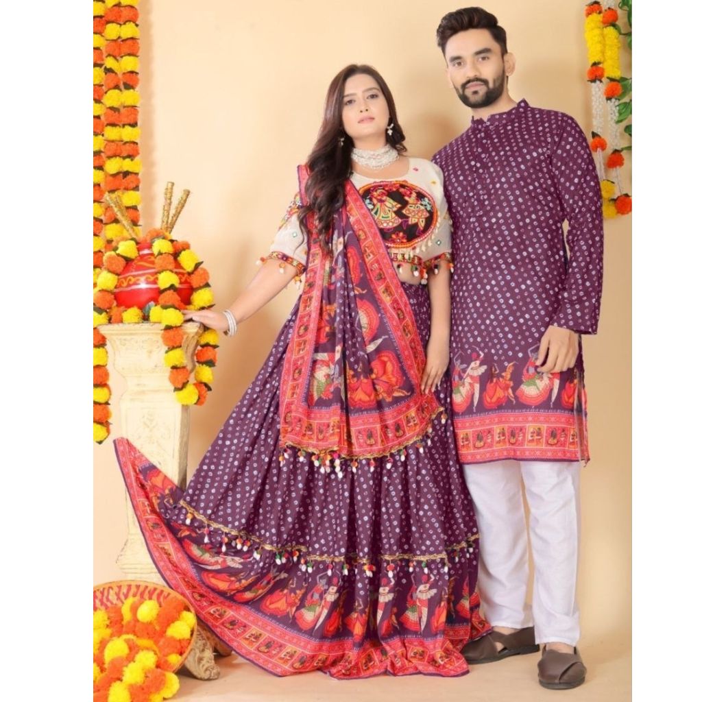A couple modeling traditional Indian ethnic wear. The woman wears a deep purple embroidered lehenga choli with a red and orange border print, and a matching patterned dupatta.