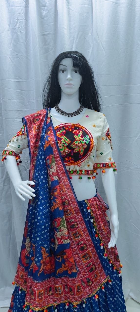 A traditional Indian ethnic wear set displayed on a female mannequin, featuring a blue printed lehenga skirt, a cream-colored embroidered blouse with colorful details, and a matching blue dupatta with red and gold patterns.