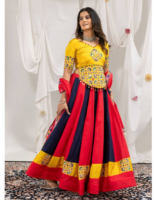 Load image into Gallery viewer, A woman models a traditional Indian ethnic outfit consisting of a bright yellow embroidered blouse and a voluminous red and navy blue skirt with yellow border details, set against a draped white fabric backdrop.
