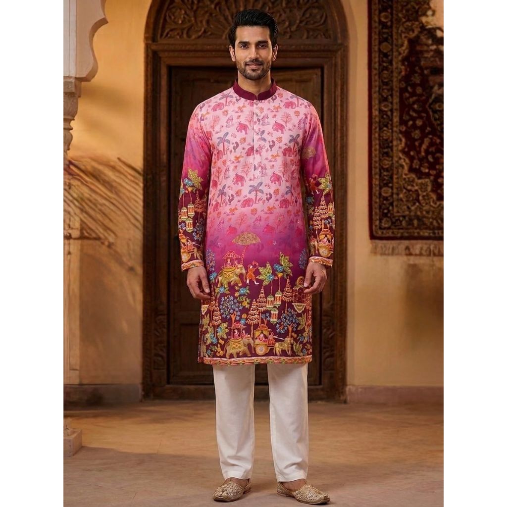A man modeling a vibrant pink and magenta printed traditional Indian kurta with colorful floral and scenic motifs, paired with white trousers and beige shoes, standing in front of an ornate wooden door.