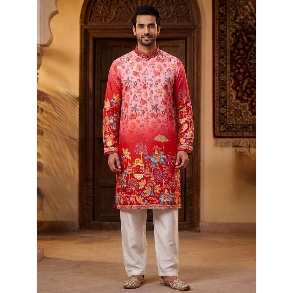 A man wearing a red and pink printed kurta with white trousers, standing in front of a traditional wooden door and wall panel.