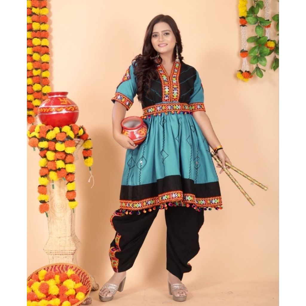 A woman modeling a traditional Indian salwar kameez suit. The outfit features a turquoise blue and black tunic with colorful embroidered borders, paired with black pants.